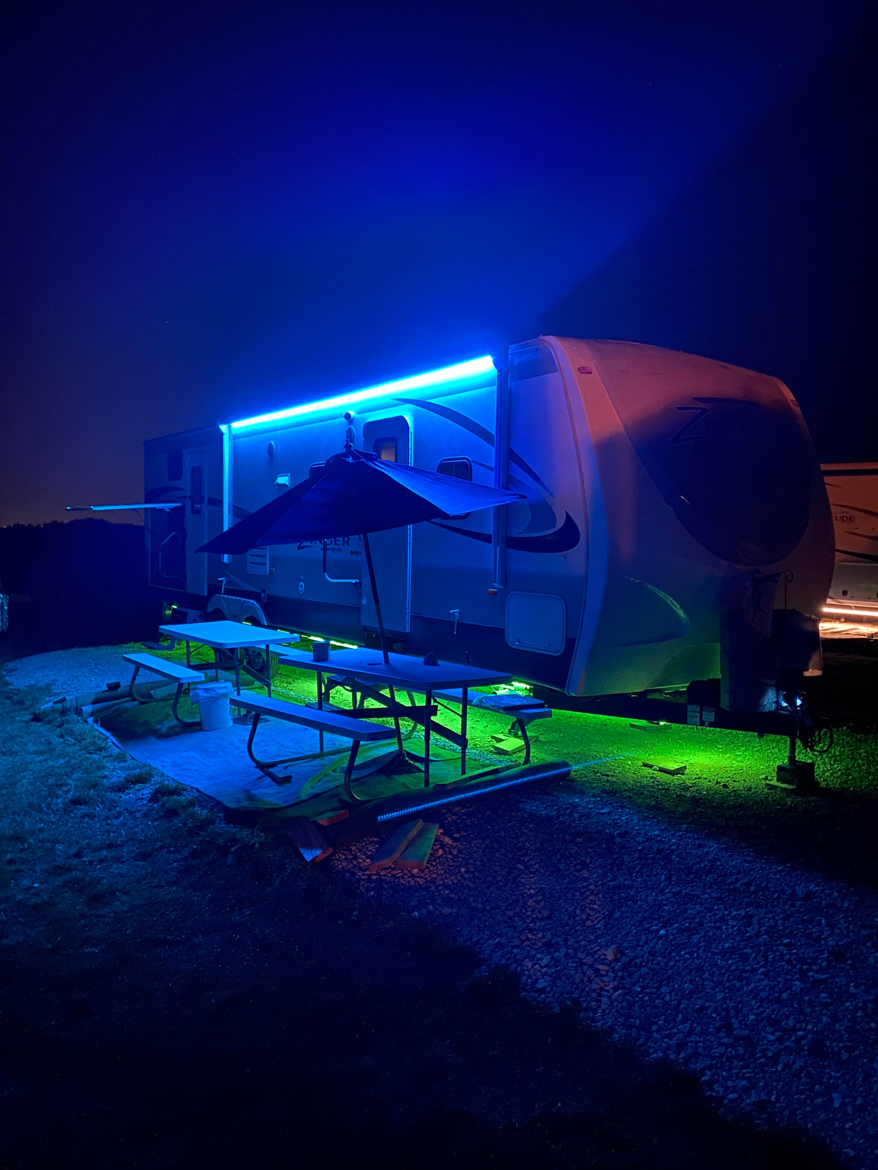 RV with neon blue and green lighting at night